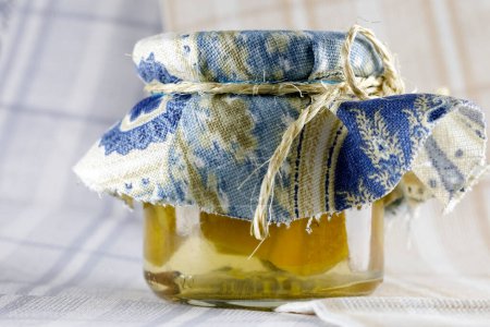 Photo for A glass jar with preserves topped with a piece of cloth and rolled up with a twine. - Royalty Free Image