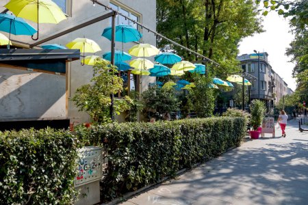 Téléchargez les photos : Varsovie, Pologne - 13 septembre 2023 : Des parapluies jaunes et bleus ont été suspendus au-dessus d'un caf en plein air dans une rue du lotissement Saska Kepa, dans le quartier Praga-Poludnie. - en image libre de droit