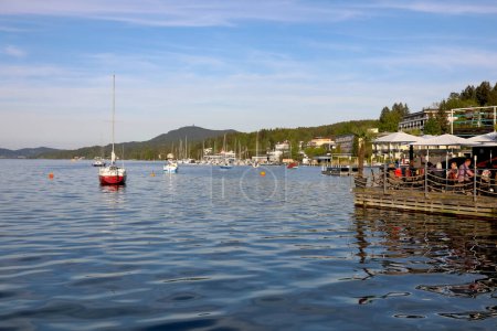 Téléchargez les photos : Velden Am Worthersee, Autriche - 4 mai 2023 : Vue générale du lac et des bateaux amarrés. Il y a un restaurant en plein air sur une jetée sur le lac - en image libre de droit