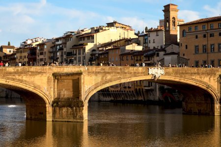 Photo for Florence, Italy - April 16, 2023: Ponte Santa Trinita is a 16th century arched bridge that spans the Arno river. This landmark of the city is illuminated by the rays of the slowly setting sun - Royalty Free Image