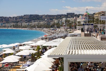 Téléchargez les photos : Nice, France - 3 mai 2023 : Bâtiments et plages le long de la côte méditerranéenne. Les plages sont souvent équipées de parasols et chaises longues pour les bains de soleil pour se détendre à l'ombre ou au soleil. - en image libre de droit