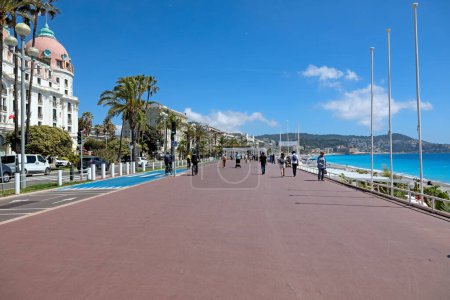 Téléchargez les photos : Nice, France - 26 avril 2023 : La Promenade des Anglais par une journée ensoleillée. Cette promenade en bord de mer est souvent visitée par de nombreuses personnes qui profitent de la vue sur l'architecture et la côte. - en image libre de droit