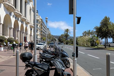 Téléchargez les photos : Nice, France - 26 avril 2023 : La Promenade des Anglais au bord de la mer est souvent visitée par des personnes profitant de la vue sur l'architecture et le littoral. Il y a plusieurs scooters garés ici. - en image libre de droit