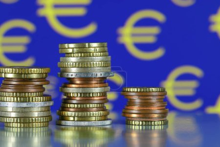 Photo for This is the currency of the European Union. The stacks of coins are shown against the yellow euro symbols on a blue background. This theme can be used to illustrate a wide range of financial topics. - Royalty Free Image
