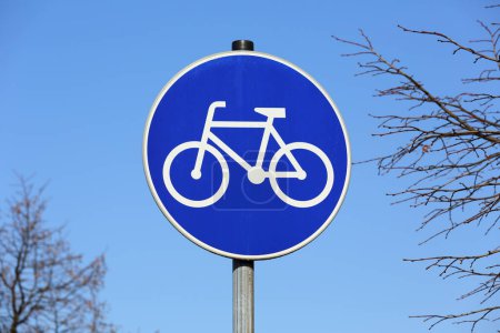 Shape of white bicycle on round blue background placed on metal pole is a road sign indicating bicycle path for cyclists is here.