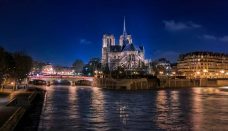 Foto de Iluminado Catedral de Notre Dame de París con la aguja, antes del incendio por la noche, la catedral gótica católica más famosa del mundo en París, Francia - Imagen libre de derechos