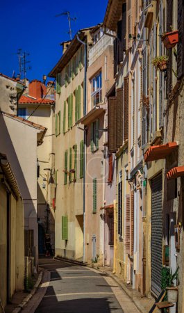 Photo for Narrow road between traditional old houses on a street near the local covered provencal farmers market in old town or Vieil Antibes, South of France - Royalty Free Image