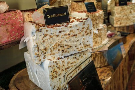 Photo for Block of fresh classic white nougat with almonds, hazelnut and honey at an artisanal candy shop in Saint Paul de Vence medieval town, South of France - Royalty Free Image