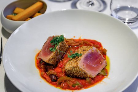 Photo for Sesame crusted rare seared tuna over piperade pepper sauce with panisse, chickpea fries at a restaurant in Saint Paul de Vence, the South of France - Royalty Free Image