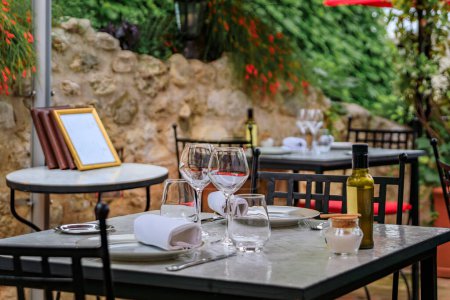 Photo for Al fresco tables waiting for customers at an outdoor restaurant in the medieval town of Saint Paul de Vence, French Riviera, South of France - Royalty Free Image