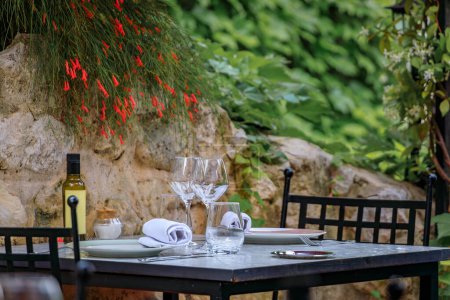 Photo for Al fresco table waiting for customers at an outdoor restaurant in the medieval town of Saint Paul de Vence, French Riviera, South of France - Royalty Free Image