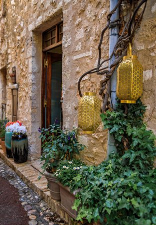 Photo for Traditional old stone houses with flowers and lanterns on a street in the medieval town of Saint Paul de Vence, French Riviera, South of France - Royalty Free Image