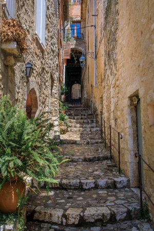 Photo for Traditional old stone houses on a steep narrow street with steps in the medieval town of Saint Paul de Vence, French Riviera, South of France - Royalty Free Image