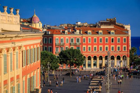 Foto de Niza, Francia - 29 de mayo de 2023: Los turistas visitan Place Massena, un importante monumento comercial y cultural con edificios coloridos adornados y Fountain du Soleil - Imagen libre de derechos