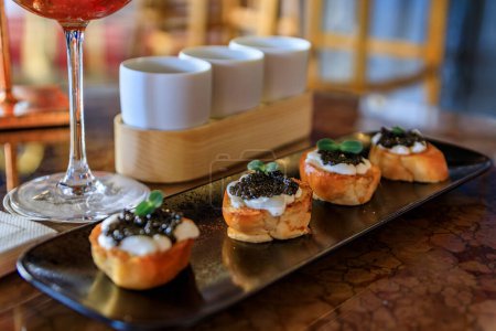 Téléchargez les photos : Mini pain grillé brioché à la crème fraîche et caviar d'esturgeon noir avec un intérieur coloré dans un restaurant de luxe, le Carre d Or, Nice, Sud de la France - en image libre de droit