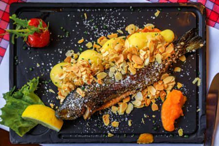Photo for Traditional French trout almondine served with potatoes, salad, carrot puree and a wedge of lemon at a winstub restaurant Strasbourg, Alsace, France - Royalty Free Image