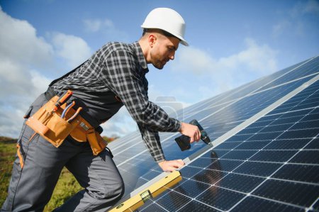 Foto de Hombre trabajador en uniforme al aire libre con baterías solares en día soleado - Imagen libre de derechos