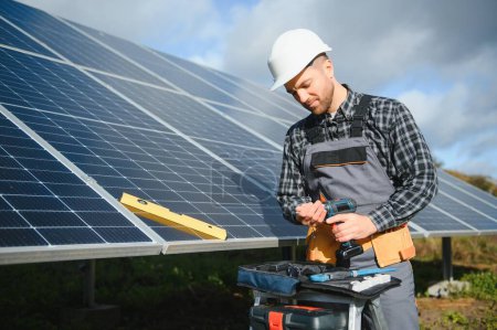 Photo for Male worker in uniform outdoors with solar batteries at sunny day - Royalty Free Image