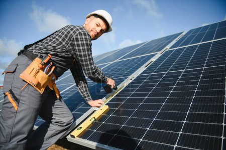 Photo for Male worker in uniform outdoors with solar batteries at sunny day - Royalty Free Image