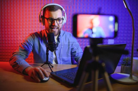 Photo for A video blogger records content in his studio. The host of the video blog is a young man who is very enthusiastic about telling his subscribers a story - Royalty Free Image