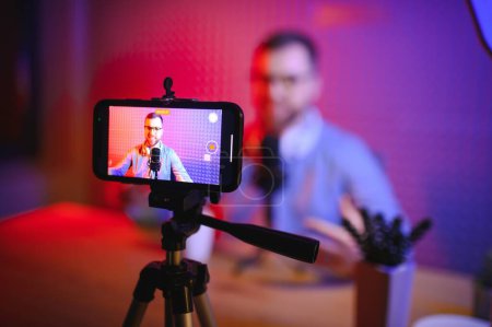 Photo for A video blogger records content in his studio. The host of the video blog is a young man who is very enthusiastic about telling his subscribers a story - Royalty Free Image