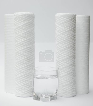 Foto de Un vaso de agua de bebida y cartuchos de filtro en fondo blanco. - Imagen libre de derechos