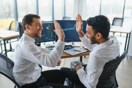 Photo for Two successful trader in formalwear pointing at display, analyzing stat and dynamic on forex charts, working in office together. - Royalty Free Image