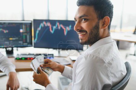 Foto de Portrait of a positive successful Indian or Arabian trader, stock market broker, Crypto charts on laptop screen. - Imagen libre de derechos
