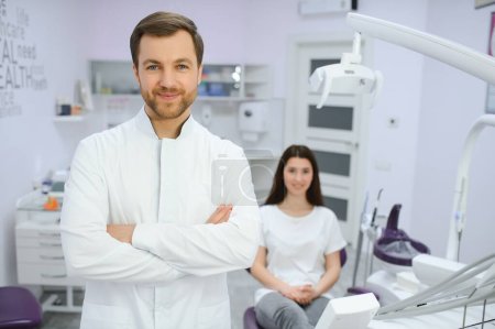 Téléchargez les photos : Dentiste masculin dans une chambre avec équipement médical et patient sur fond - en image libre de droit