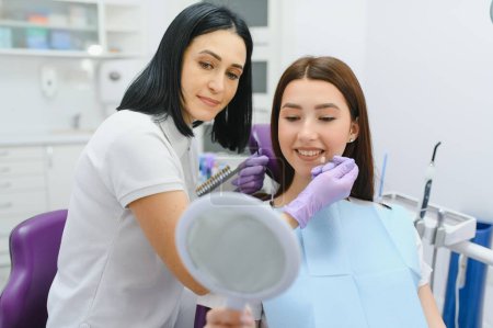 Photo for Young woman choosing color of teeth at dentist. - Royalty Free Image