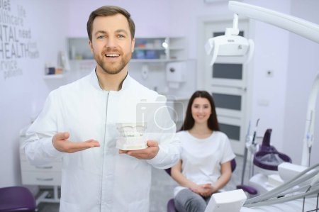 Photo for Dental Center. Portrait Of Smiling Middle Eastern Dentist Doctor Posing At Workplace, Handsome Arab Stomatologist Standing In Modern Clinic Interior, Ready For Check Up With Patient. - Royalty Free Image