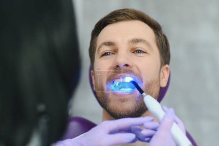 Closeup portrait patient in dental office - ultraviolet light equipment.