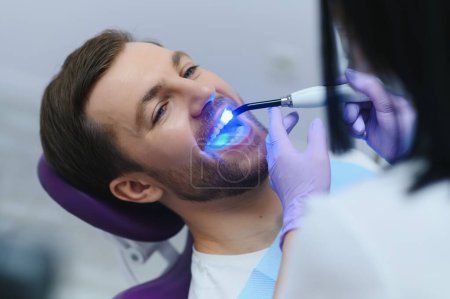 Téléchargez les photos : Portrait rapproché patient en cabinet dentaire - équipement de lumière ultraviolette
. - en image libre de droit