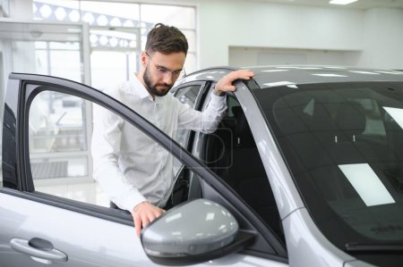 Photo for A man examines a car in a car dealership. - Royalty Free Image