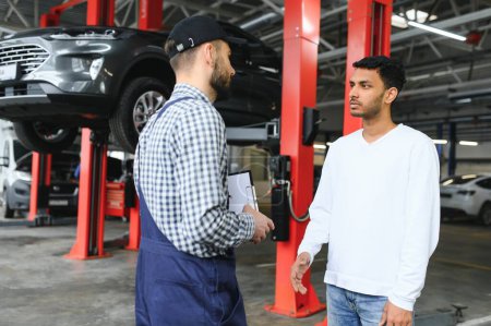 Un mecánico en un servicio de autos está hablando con el dueño de un auto indio. Concepto de servicio de coche