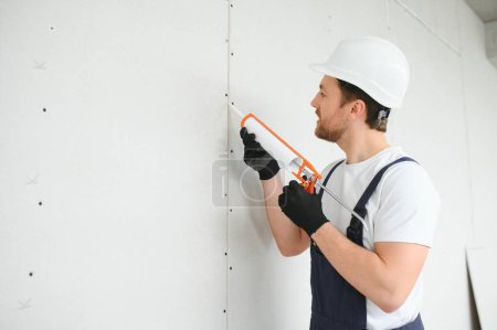 Téléchargez les photos : Ouvrier professionnel appliquant le mastic de silicone avec le pistolet de calfeutrage sur le mur. - en image libre de droit