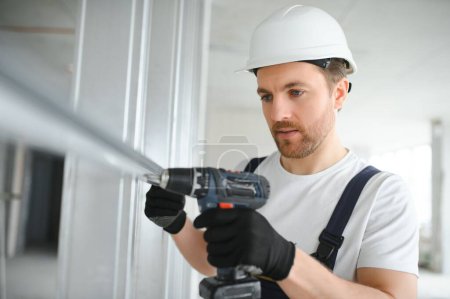 Photo for Drywall worker works on building site in a house - Royalty Free Image