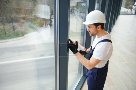 Foto de Trabajador de la construcción instalando ventana en casa - Imagen libre de derechos