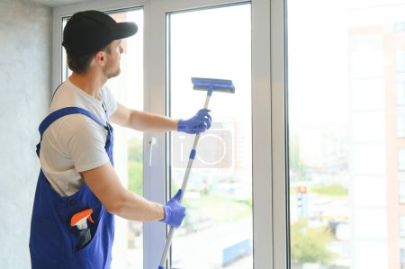 Photo for Cheerful male person cleaning window. - Royalty Free Image