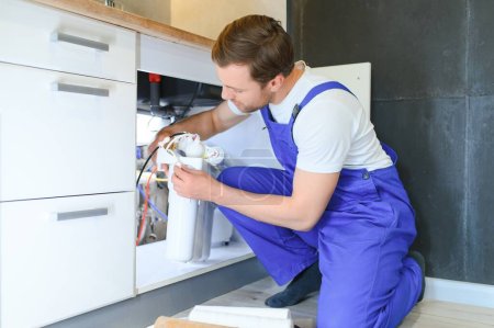 Plumber installs or change water filter. Replacement aqua filter. Repairman installing water filter cartridges in a kitchen. Installation of reverse osmosis water purification system
