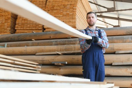 Récolte du bois pour la construction. Carpenter empile les planches. Contexte industriel. Flux de travail authentiques.