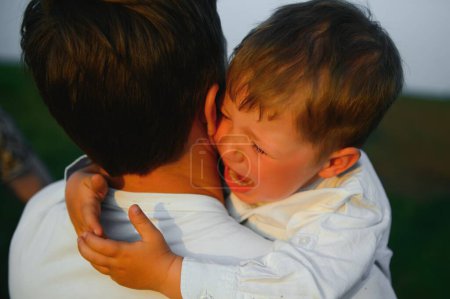 Foto de Día de los Padres. Triste hijo abrazando a papá en el fondo del bosque con espacio para copiar. Concepto de relación padre-hijo. - Imagen libre de derechos