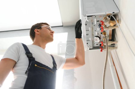 Téléchargez les photos : Plombier professionnel vérifiant une chaudière et des tuyaux, concept de service de chaudière. - en image libre de droit