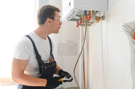 Photo for Gas engineer checking and cleaning a boiler during the inspection at home. - Royalty Free Image