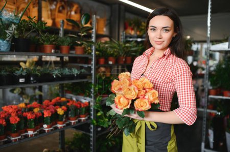 Téléchargez les photos : Portrait de fleuriste féminine dans sa boutique de fleurs - en image libre de droit