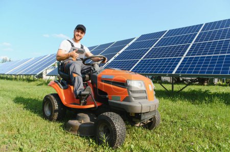 A man mows the grass near the solar panels. Green energy.
