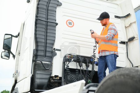 Foto de Vista de un conductor conectando los cables de alimentación al remolque de un camión comercial - Imagen libre de derechos