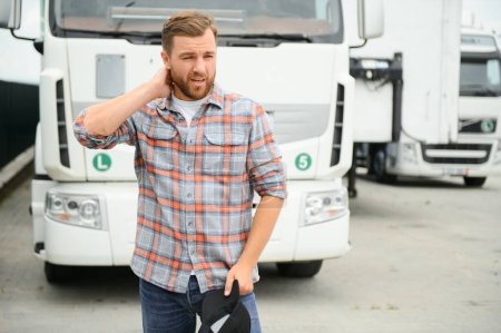 Photo pour Fatigué de la route, le camionneur se tient près de son camion blanc - image libre de droit