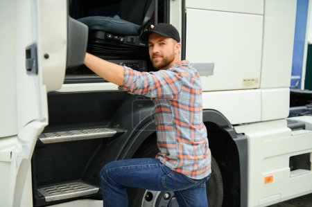 Trucker ouvre la porte et s'assoit dans son camion garé avec une remorque. Le conducteur poursuit le voyage après s'être arrêté.
