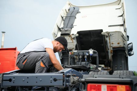 Téléchargez les photos : Mécanicien réparant le camion en service - en image libre de droit